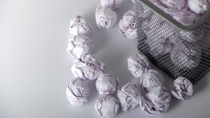 A trashcan full of crumpled paper on white background close up