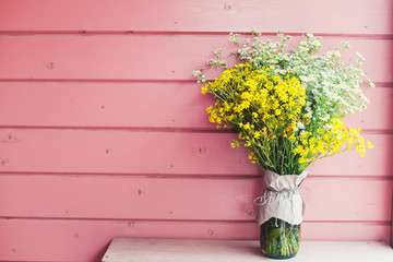  Home decor. Wildflowers in a vase on a background of wooden pink boards.