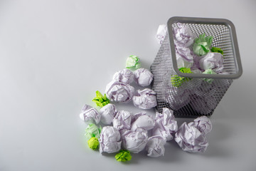 A trashcan full of crumpled paper on white background close up