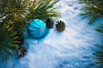 Blue Christmas ball on the table with fir branches cones and snow