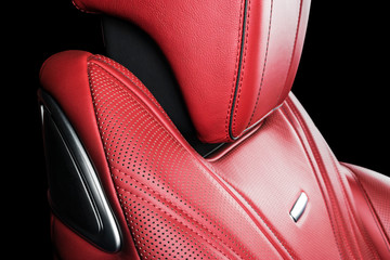 Red leather interior of the luxury modern car. Perforated red leather comfortable seats with stitching isolated on black background. Modern car interior details. Car detailing. Car inside