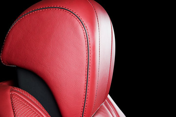 Red leather interior of the luxury modern car. Perforated red leather comfortable seats with stitching isolated on black background. Modern car interior details. Car detailing. Car inside