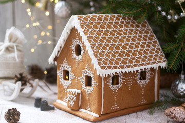 Gingerbread house and Christmas trees on a luminous background. Bokeh effect.