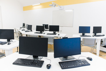 office room with computer tables with keyboard and mouse with a board and a projector 