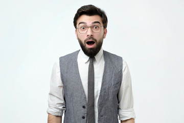 Young spanish man with shocked facial expression, isolated over white background