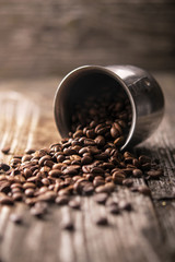 Coffee grains are scattered on a wooden table in the morning light . Rustic style. Copy space