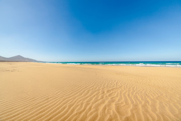 Fototapeta na wymiar Cofete beach, Fuerteventura, Canary Islands, Spain. Amazing Cofete beach with endless horizon. Volcanic hills in the background and Atlantic Ocean.