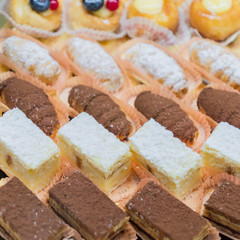 Pastry shop display window with variety of mini desserts and cakes, selective focus
