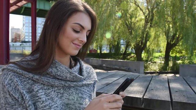 Young millennial beautiful happy busy woman girl outside walking and texting on cellphone mobile smartphone sending messages on social media and updating newsfeed on mobile device