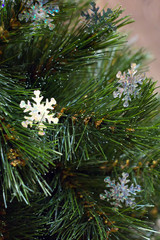 Fototapeta na wymiar Big sparkle snowflakes on christmas tree brunch with bokeh effect on soft background in vertical align