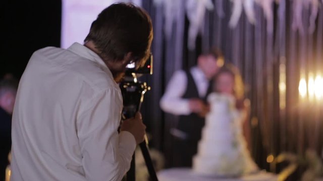 Image of movie shooting or photographing on Wedding day. Video production with camera equipment at indoor location. Loving wedding couple the bride and groom on the background.