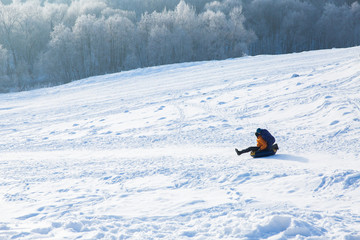 People riding from the snowy hill on the field in winter forest