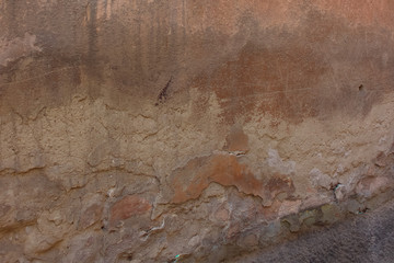 The old shabby wall, which shows several layers of old plaster, scratching, and traces of the old paint