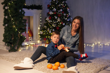 mother and son celebrate the new year at a Christmas tree with presents lights Garland