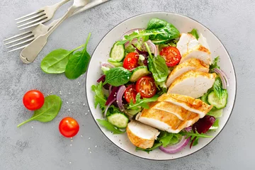 Wall murals Food Grilled chicken breast, fillet and fresh vegetable salad of lettuce, arugula, spinach, cucumber and tomato. Healthy lunch menu. Diet food. Top view