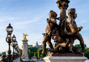 Obraz premium Widok na most Pont Alexandre III. Zbliżenie na pomnik dzieci o nazwie Ronde d'Amours z lampami w tle - Paryż, Francja.