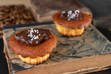 Tasty cupcakes decorated with chocolate and book loss. Dessert on a wooden table in the kitchen.
