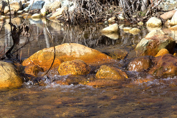 A close-up of water flowing over orange rocks 