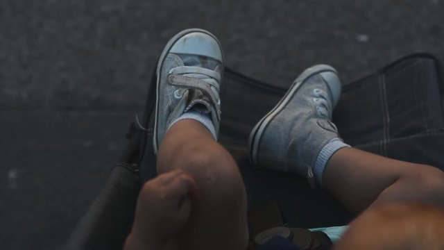 Baby legs in dirty shoes in a stroller