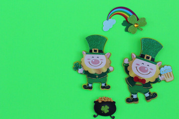 two leprechauns one dancing with a beer laying flat with a rainbow and a pot of gold on a green background with writing space