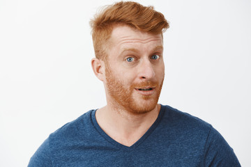 Headshot of intrigued good-looking ginger male with bristle in blue t-shirt turning at camera with...