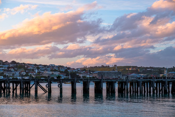 Obraz premium Beautiful sunset at the dock. Blue sky and Ocean with town view. Omaru, New Zealand.