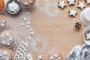 Top view of the table with sugar-sprinkled muffins, fondant icing and Christmas star cookies on...
