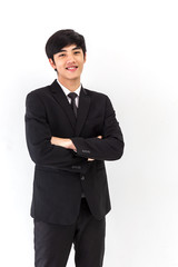 Obraz na płótnie Canvas A young asian businessman in a black suit and white shirt, standing against a white background smiling towards camera. Portrait of handsome man smiling with arms crossed on isolated white background.