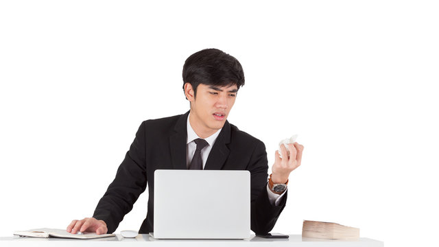 A handsome businessman crunched report with displeased emotion face. A young CEO furious with mistake report. Business man hand crunching a piece of white paper in anger on white background.