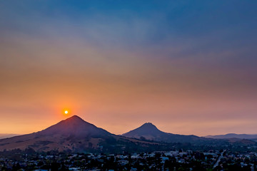 Silhouetted Peaks at Sunset with Orange Ball