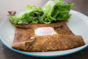 Filled with smoked ham, smoked salmon, grated cheese, sunny side up egg served with a green salad