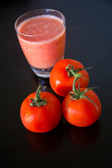 A glass of tomato juice with fresh tomatoes