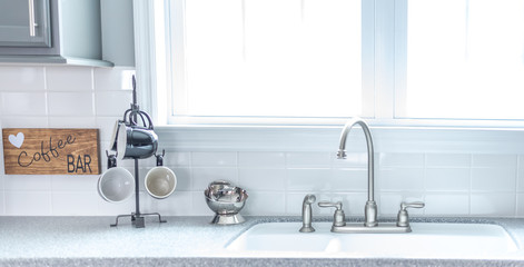 Kitchen sink with coffee mugs by bright window