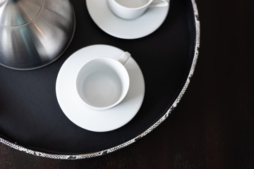 White tea cup and saucer on black platter