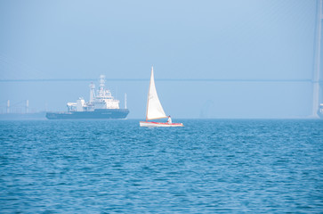 Russia, Vladivostok, July 2018: Sailboat and ship at sea. Primorsky Krai, Bosphorus-East Strait.