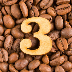 3, Number on wood- background of coffee beans.