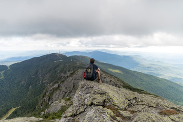 a hiker enjoys the unparalled views atop a high mountain range in Vermont