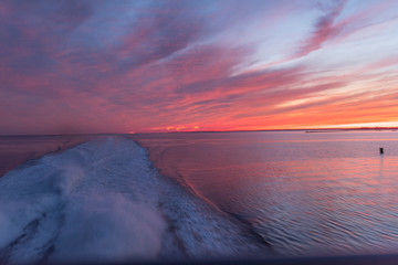 wake of a power boat with the sun setting