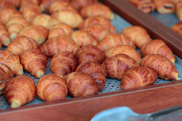 A lot of ruddy croissants on the buffet. A cropped shot, close-up, horizontal, side view. The concept of food and service.
