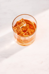 glass of whiskey or tea with ice on marble background vertical