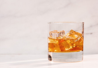 glass of whiskey or tea with ice on marble background horizontal side view