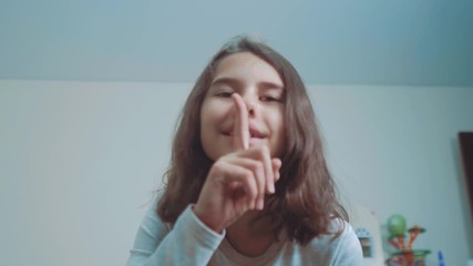 little teenage girl gesture finger quiet. slow motion video. girl putting finger up to lips and saying shh. lifestyle teen girl asks for silence