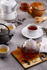 Tea card. Different in appearance teapots on a gray background, different types of tea. Assortment. Tea still life.