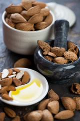 Bowl of unpeeled almonds, marble pounder and freshly made almond oil, close-up
