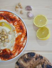plate of Traditional  homemade hummus on rustic table background with red paprika olive oil ,garlic ,  lemon ,  tahini and  pita bread  Image