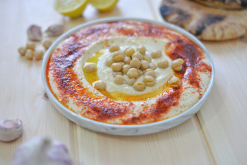 plate of Traditional  homemade hummus on rustic table background with red paprika olive oil ,garlic ,  lemon ,  tahini and  pita bread  Image
