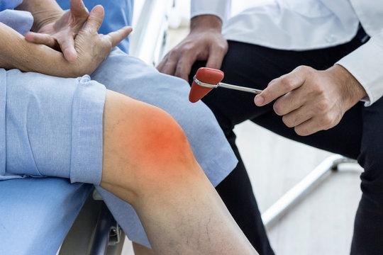 Doctor checking reflexes of the knee of her patient in medical office