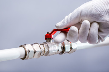 Open A Fuel Tap. Opens up concept. Hand of male opens tap on grey background.