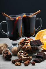Two cups with ready mulled wine with anise, cinnamon and nuts around