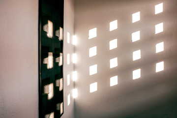 Shadow of light shine through the concrete wall, Light through the squares of concrete wall in home, White concrete grid background, White square channel on wall of home with flare light from sun